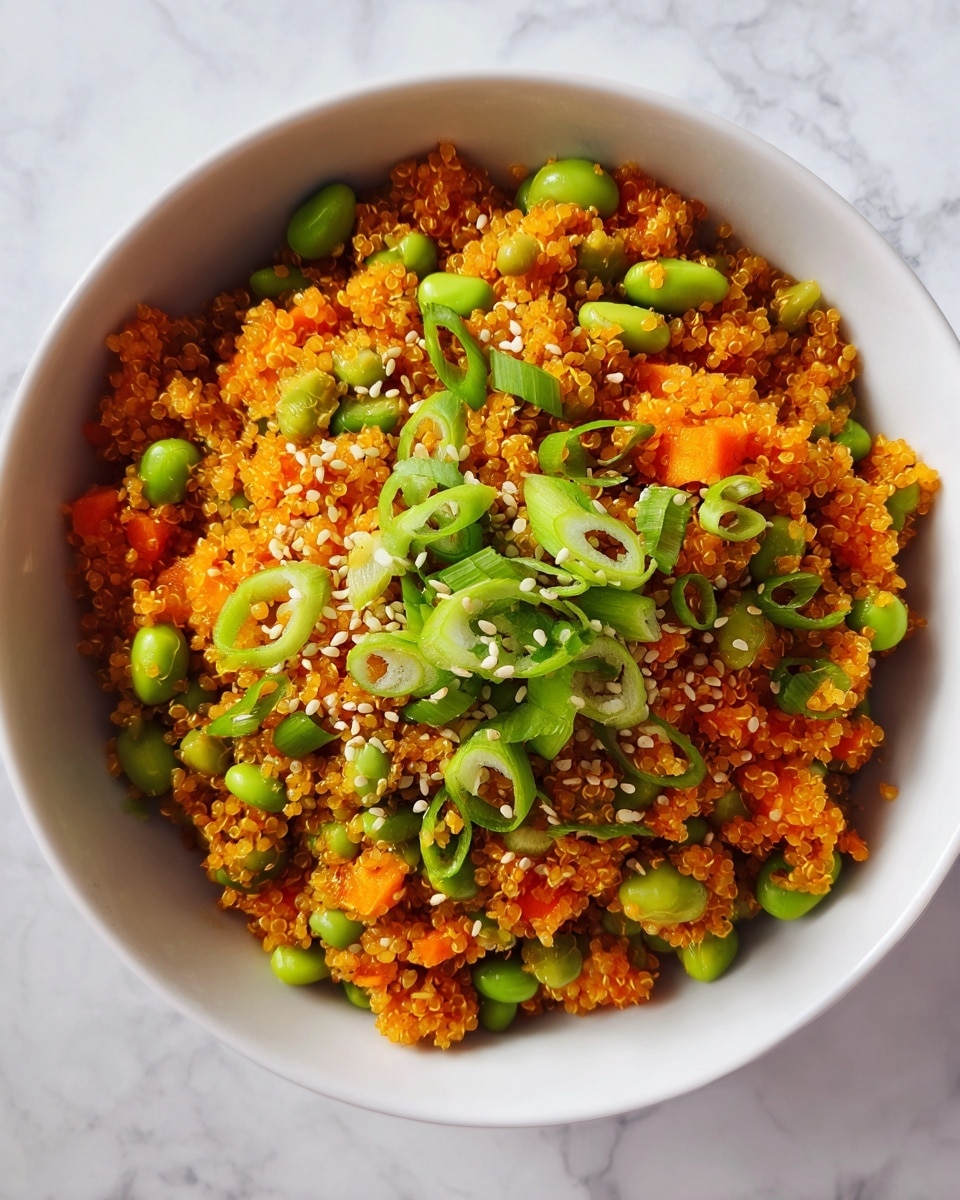 The image shows a close-up of a bowl filled with a colorful quinoa salad. The base layer is golden quinoa mixed with small orange carrot pieces evenly spread throughout. Bright green edamame beans and chopped green onions are scattered uniquely on top and throughout the salad, adding bursts of fresh green color. Small white sesame seeds are sprinkled across the whole dish, adding texture and tiny white highlights. The bowl is white with a soft, textured finish, and the scene is set against a white marbled surface, with warm natural light making the colors look vibrant and fresh. photo taken with an iphone --ar 4:5 --v 7